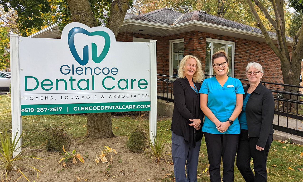 women dental team in front of sign