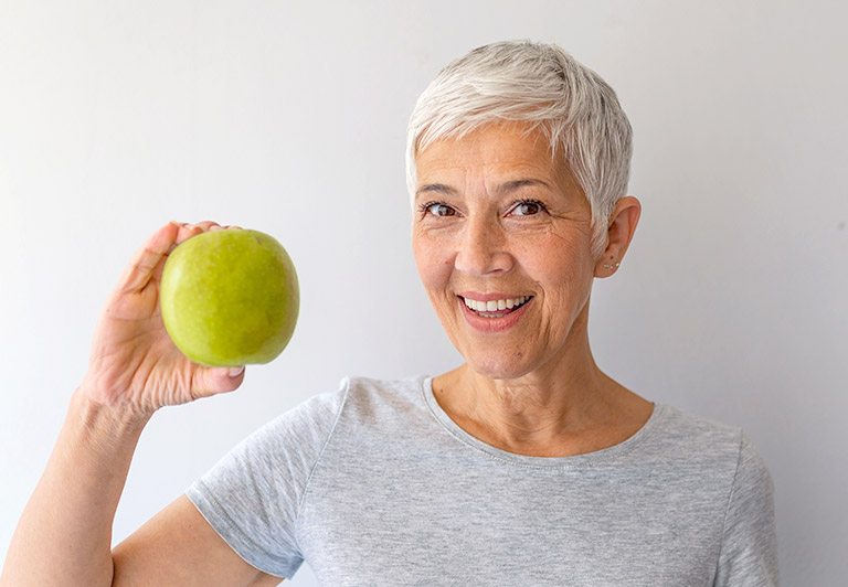 senior woman holding green apple