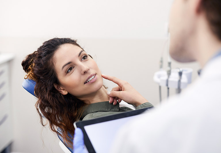 woman pointing at cheek with dentist